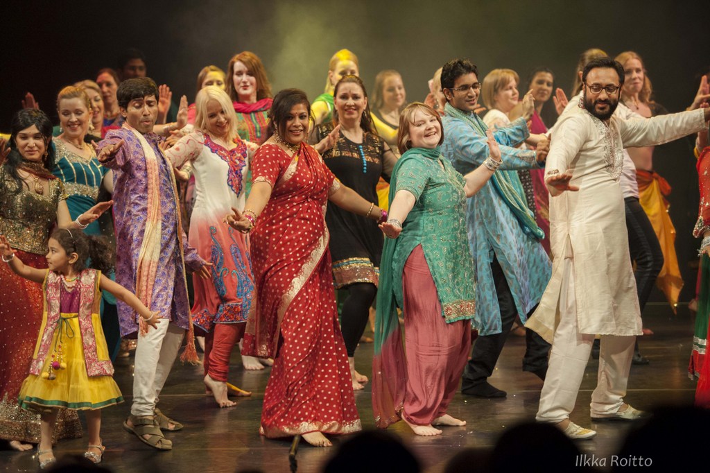 Bollywood-aiheisen näytelmän Temporary Livesin näyttelijät, ohjaaja ja tuottajat tanssimassa loppukiitostanssia Kanneltalon lavalla. Tanssitapahtuma.